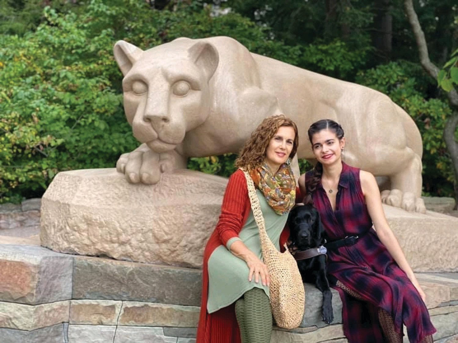 WE ARE: Aria Mia Loberti poses with her mother, Audrey, and her guide dog Ingrid, taken in front of the Nittany Lion on the Penn State campus last October.